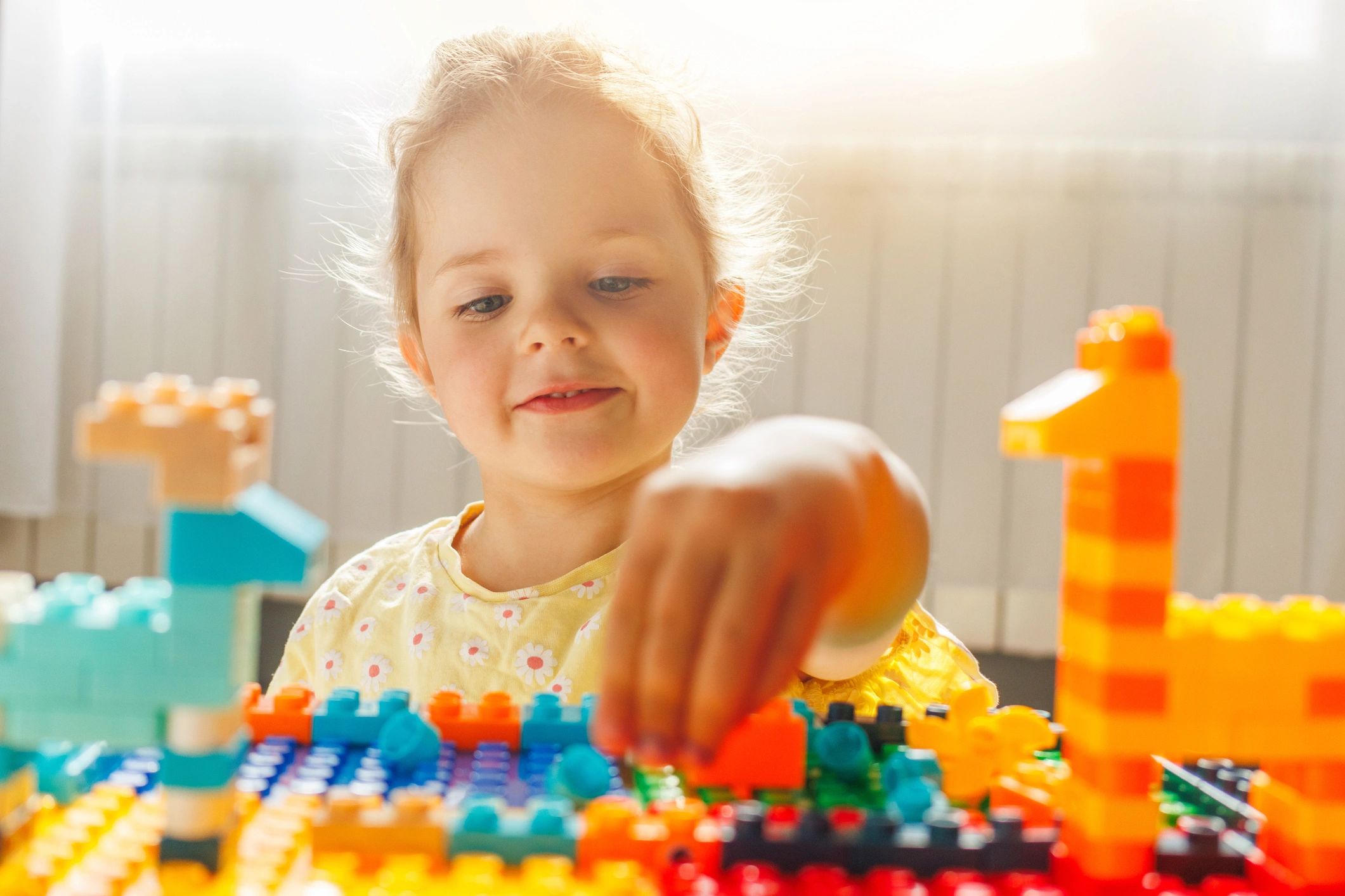 Young child reaching for colourful construction blocks