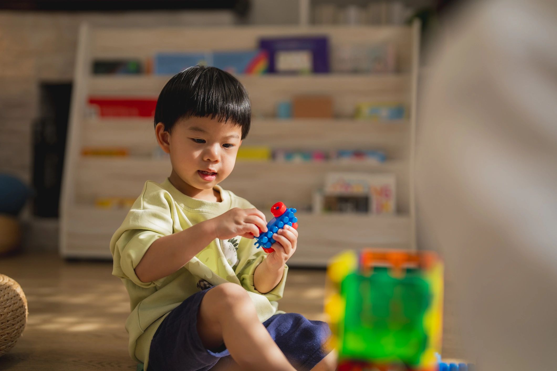Toddler building a colourful block tower with help from an adult