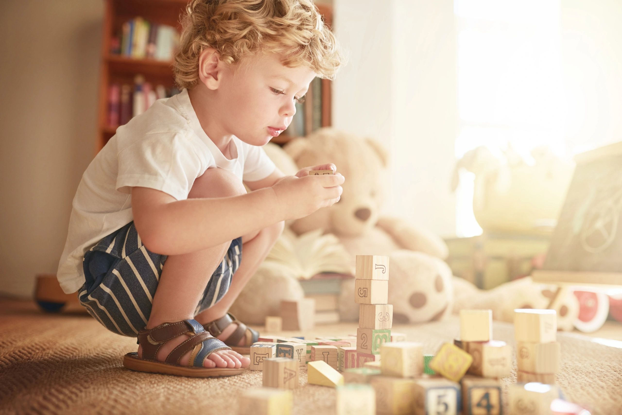 Toddler playing with wooden building blocks at home